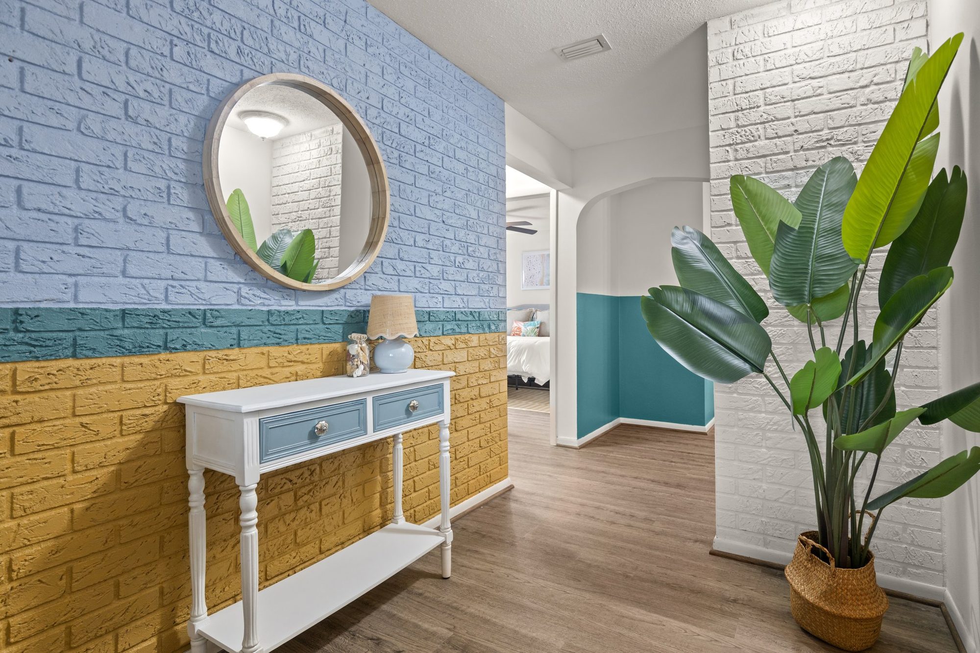 Coastal bathroom with a round mirror and white brick accent wall at Sunset Escape