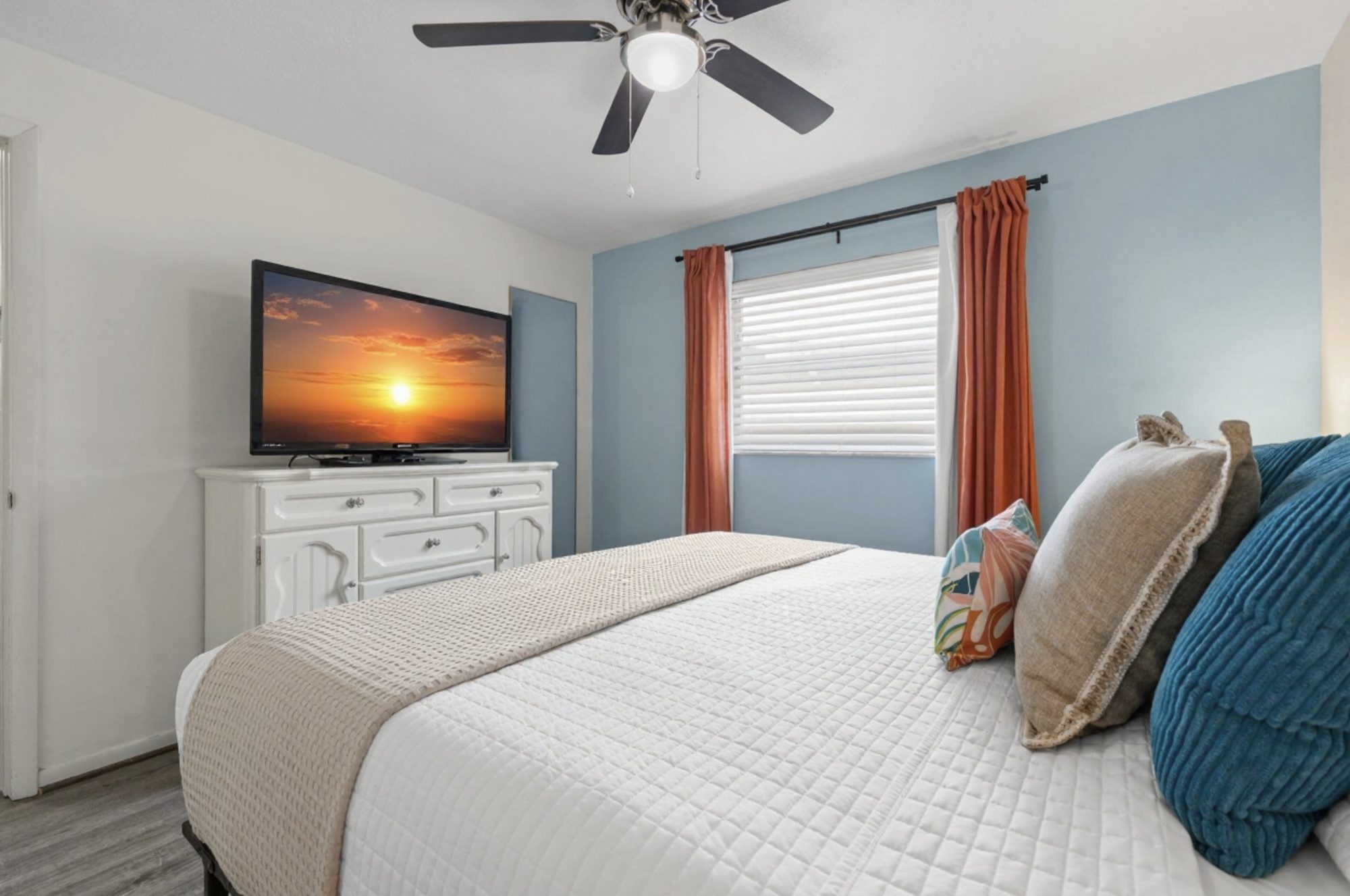 Primary bedroom at Sunset Escape with a queen bed and a sunset scene on the TV