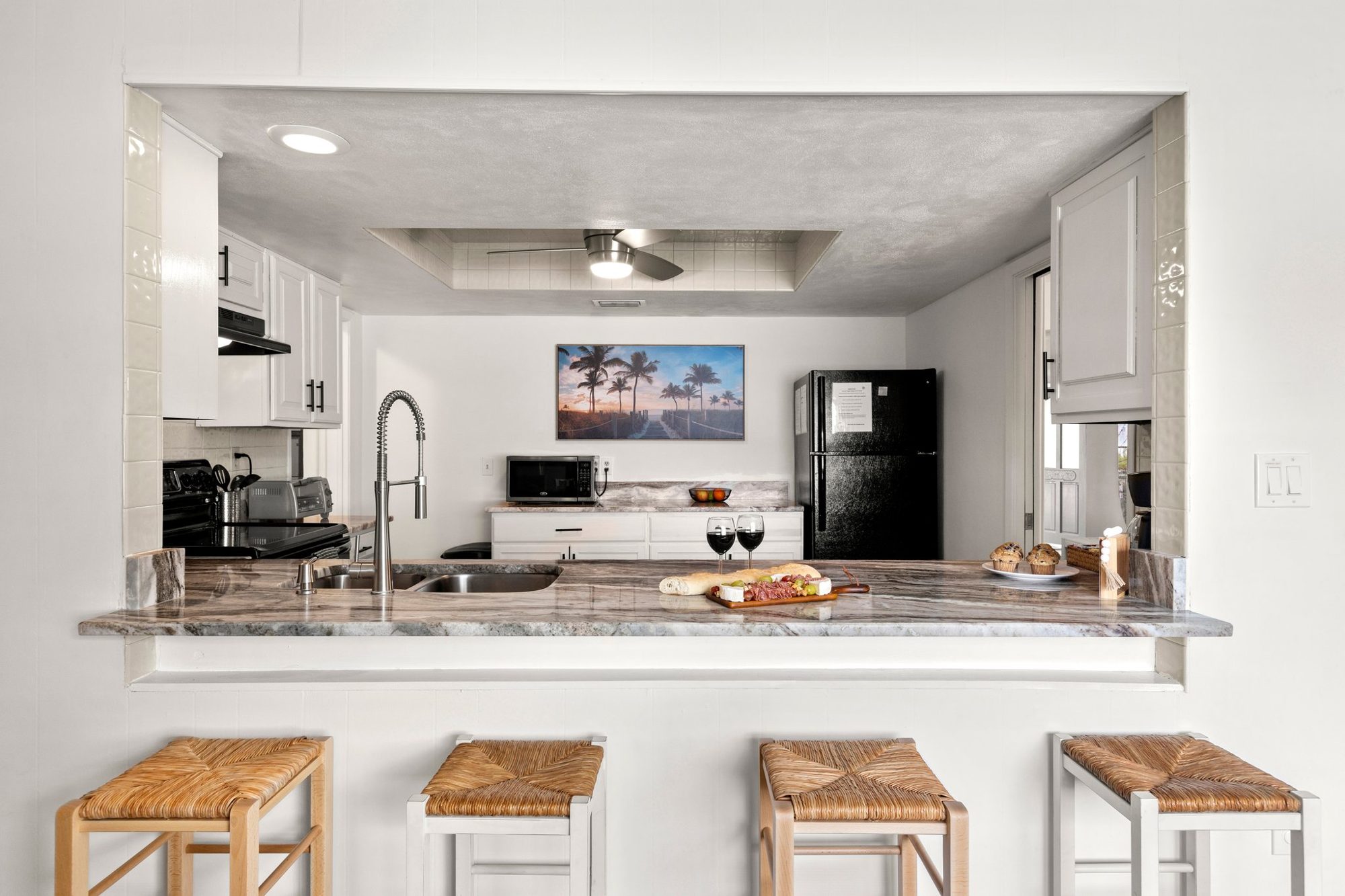 Fully equipped open kitchen with a marble breakfast bar and coastal wall art at Sunset Escape
